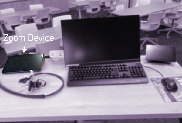 Tabletop with monitor, keyboard, cables, mouse, zoom device pictured. The words: "Zoom Device" are displayed above an arrow.