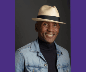 Dr. James sits for a professional headshot wearing a straw hat, black turtleneck and denim jacket.
