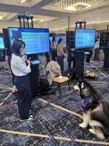 UW live mascot Dubs II sits while a student presenter gives an ePoster presentation.
