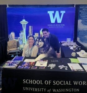 Two staff members pose with UW live mascot Dubs II at the UW SSWR exhibit booth.