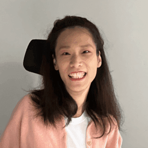 Jae Kim smiles for the camera while wearing a peach-colored cardigan.