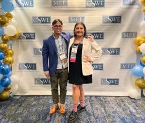 Jon Torres and Vania Buck pose in front of a backdrop with the CSWE and MFP Fellows logos printed on it.