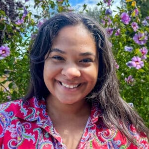 Miranda Sullivan, wearing a red patterned shirt, smiles for the camera.