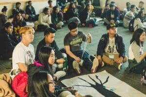 Students sit on the ground during an assembly.