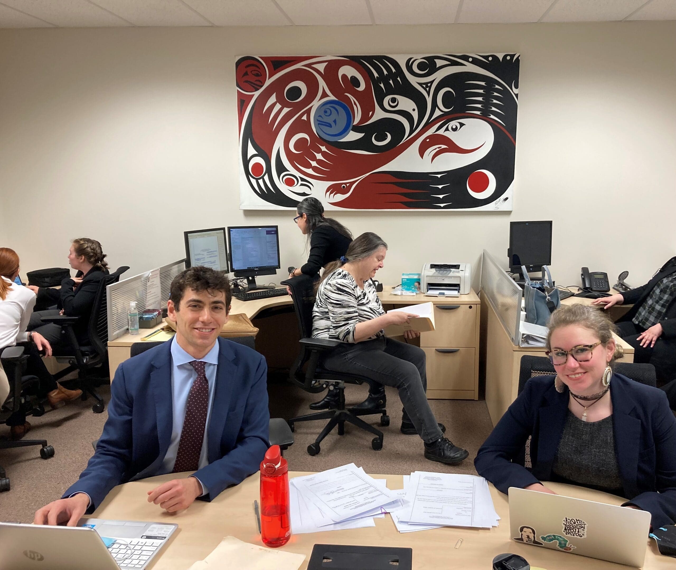 MSW and law students pose for a picture in a busy office.