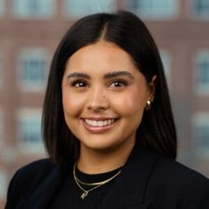 Professional head shot of Melanie Morris, a young female with short cropped dark hair wearing a black shirt.