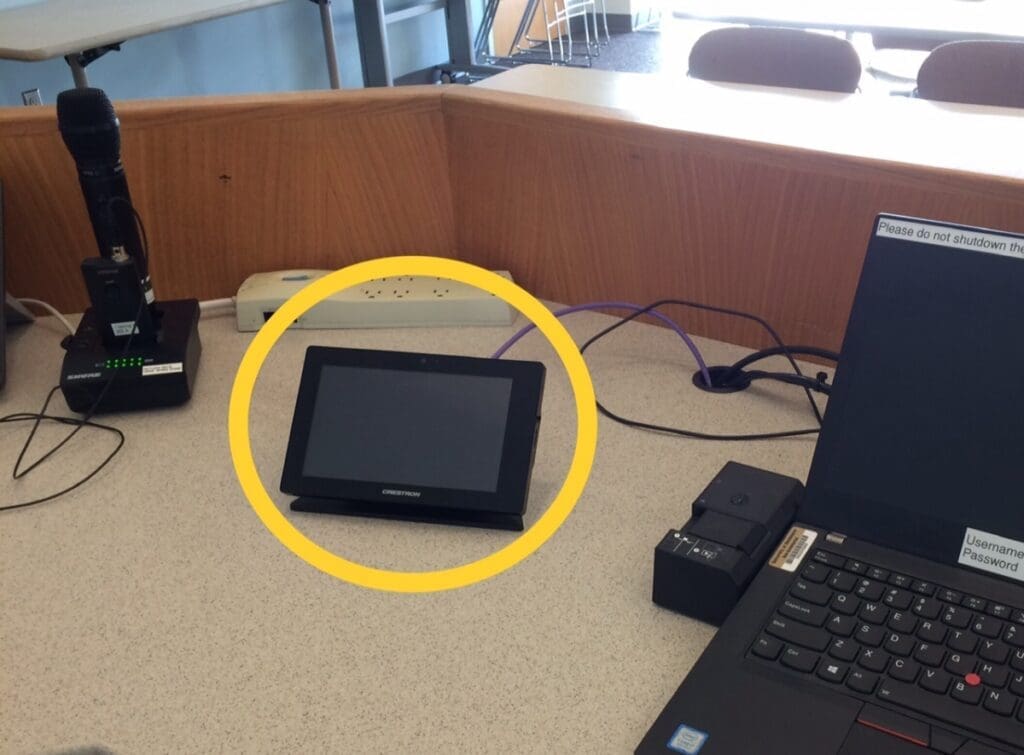 Digital touch screen display sitting on top of a podium desk in a classroom