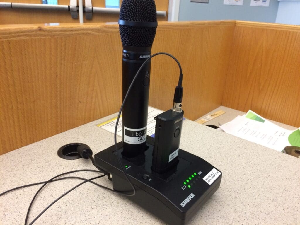 Black microphone standing upright in a charging station on a podium.